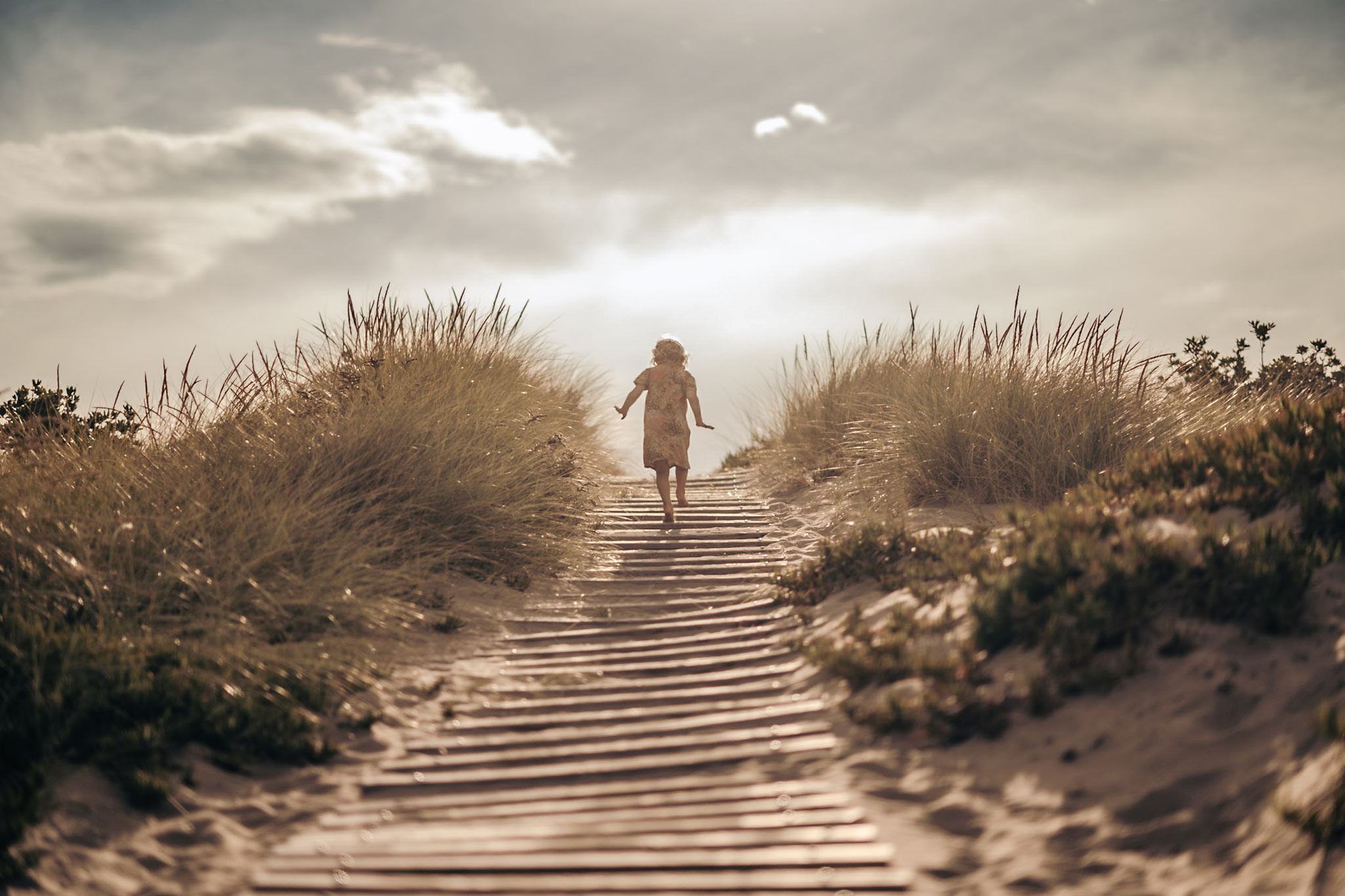 child walking up a path in sand dunes