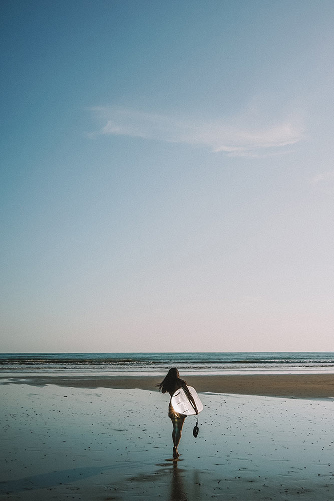 Woman with surfboard walking toward to ocean