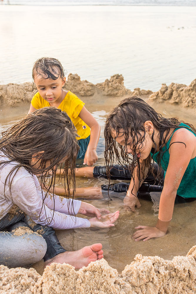 Children in wet clothes playing on the beach