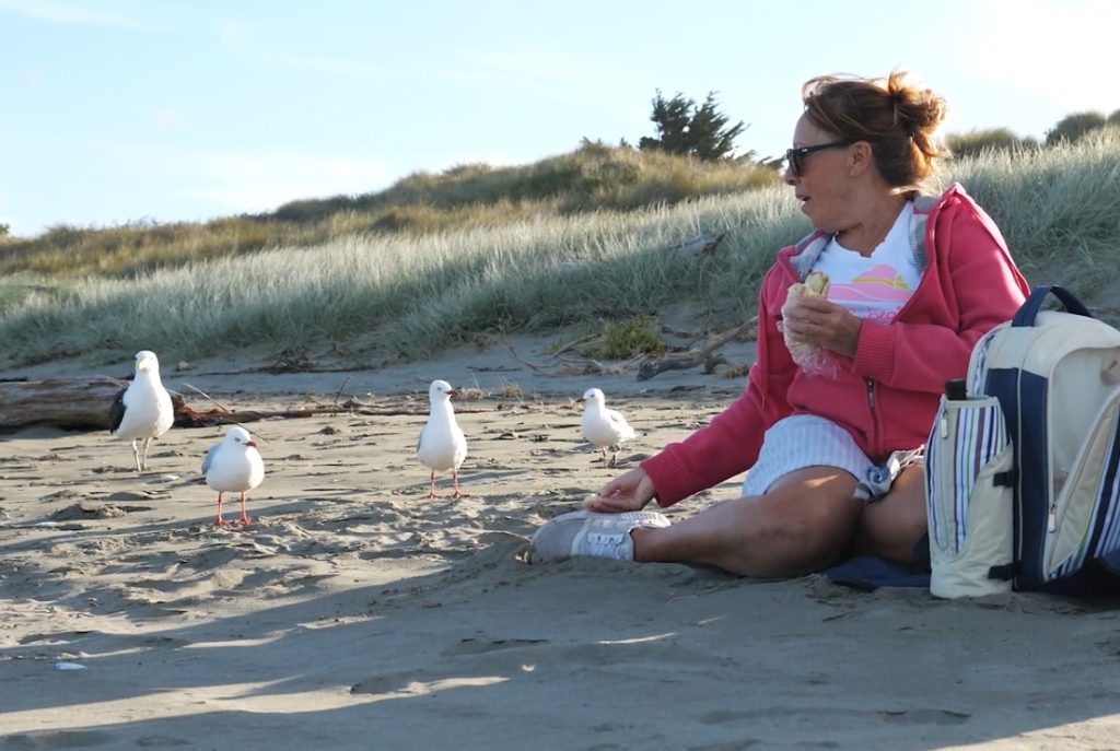 Woman feeding sea gulls on the beach